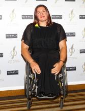 A picture of a woman in a wheelchair posing for a picture during a gala ceremony.