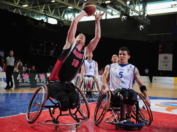 A picture of a man in a wheelchair shooting a ball in a Wheelchair Basketball match