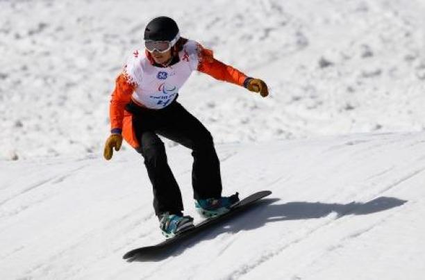 A female snowboarder rides down a slope