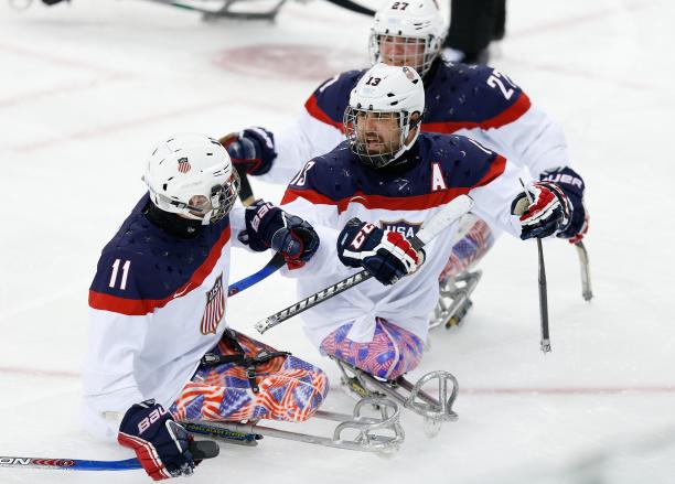 An ice sledge hockey player skates up to his teammate to celebrate.