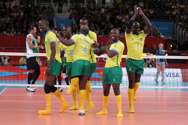 Six men celebrating on a volleyball field.