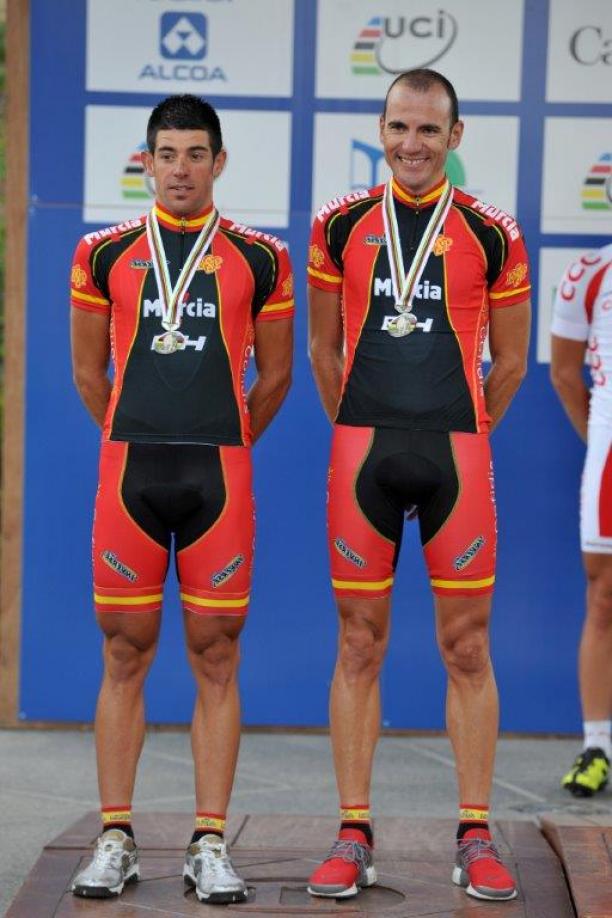 Two men stand on a podium with their medals