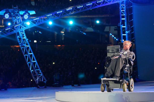 A picture of a man in an electrical wheelchair talking during a ceremony
