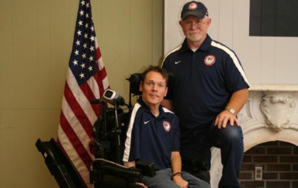 A picture of a man in an electric wheelchair posing for a picture with another man