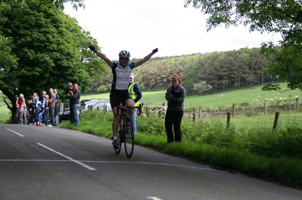 A picture of a woman on a cycle celebrating her victory