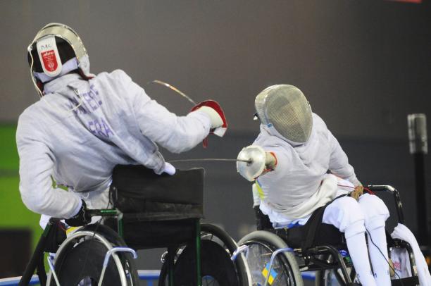 A picture of 2 mens in wheelchair practising fencing