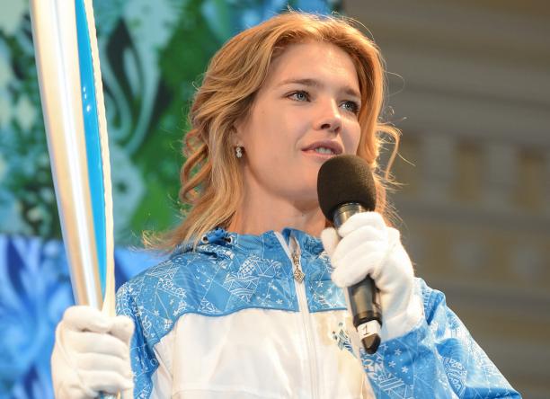A picture of a woman holding a torch and speaking on a microphone.