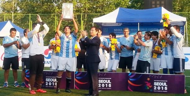 Group of men standing behind a banner holding a cup in the air.