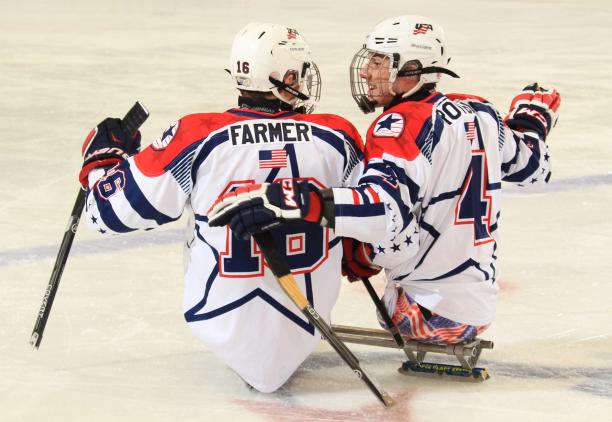 Two sledge hockey players on the ice, in a conversation