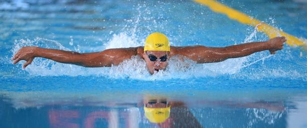 Man with yellow sim cap swimming butterfly