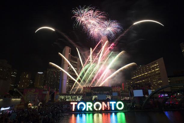 Fireworks in different colors illuminate the night above the 3D Toronto sign