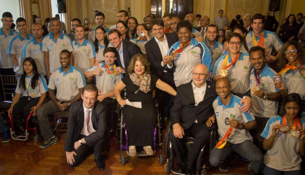 Group shot of athletes in Brazilian  team uniforms and some people in suits.
