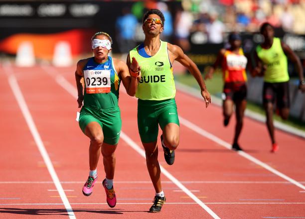 Terezinha Guilhermina Lyon A visually impaired athlete runs with her guide on the track of a stadium.