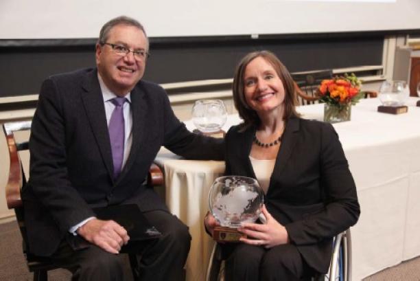Dr. Cheri Blauwet Woman in wheelchair holds trophy and poses with man.