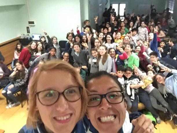 Selfie of two women smiling with many kids in the background