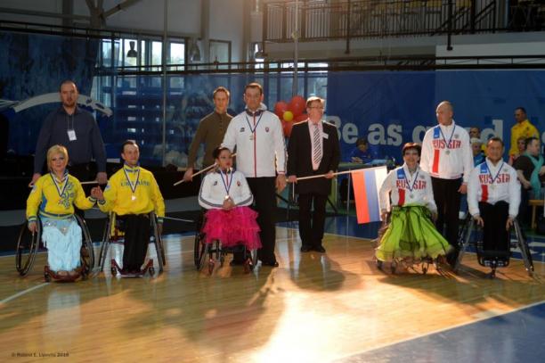 Athletes in wheelchairs and standing pose for a group photo