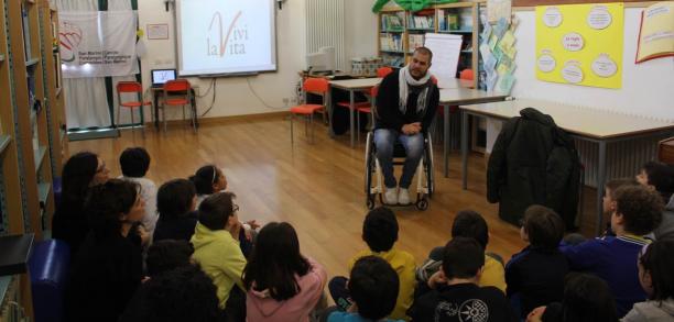 Man in a wheelchair talking to a class of school children