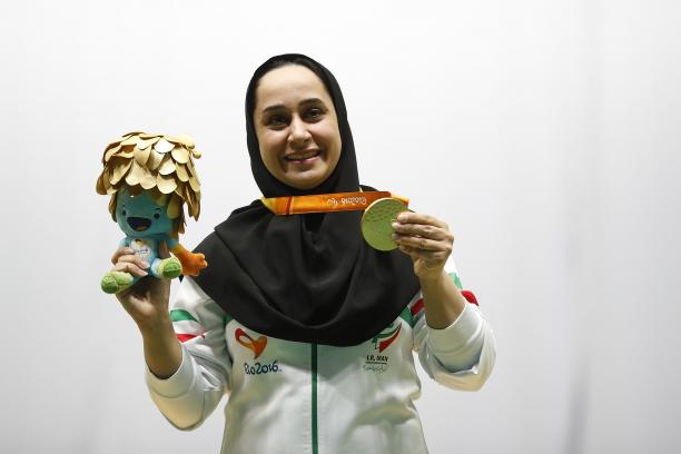 Woman with headscarf poses with medal and mascot in her hand