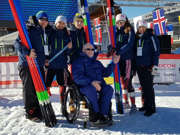 POCOG, Agitos Foundation support more than 30 NPCs with winter sport equipment Group picture with skiers and man in wheelchair