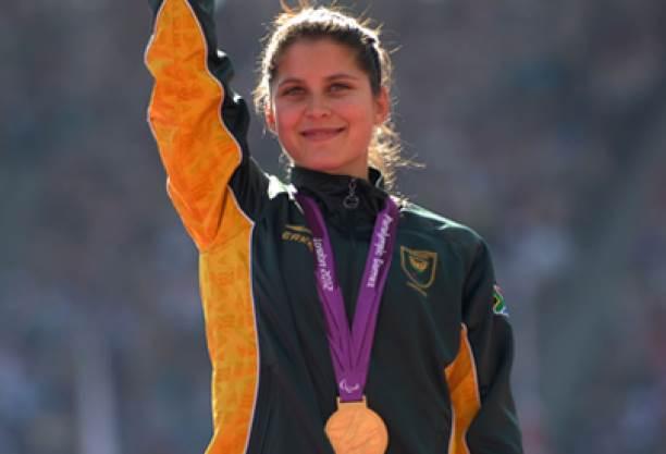 A picture of a woman with a gold medal around her neck during a medal ceremony.