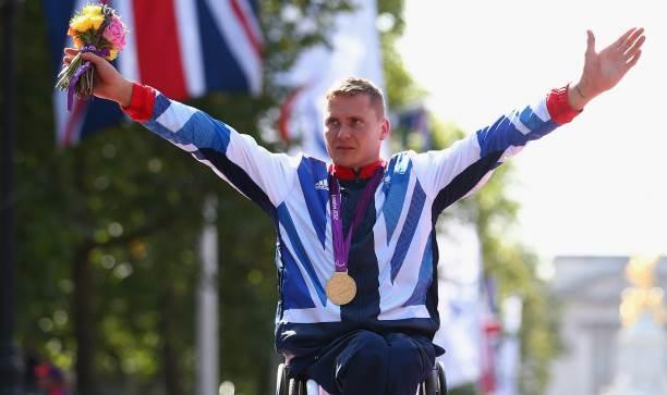 A picture of a man in wheelchair celebrating his victory with a gold medal around his neck