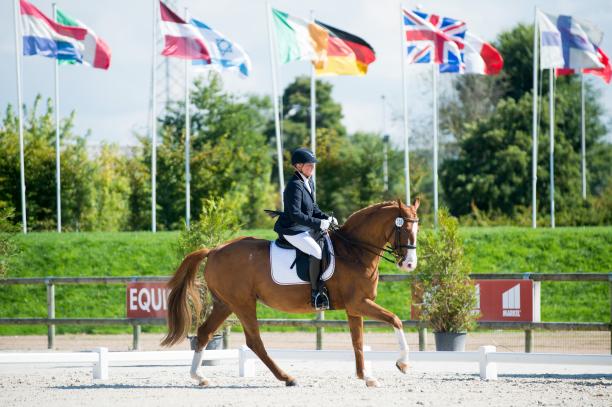 Germany's Hannlore Brenner - equestrian Woman riding a horse with various nation's flags in the background