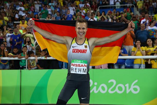 Man holds up German flag and smiles