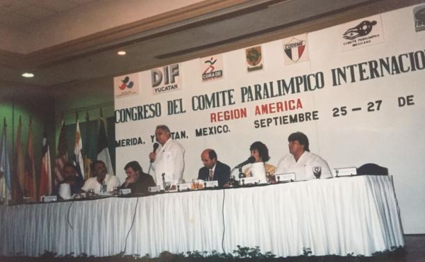 APC General Assembly a group of men speak at a table