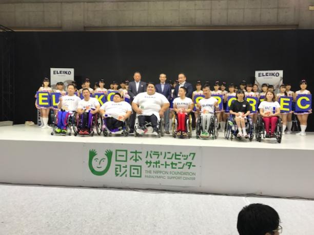 Siamand Rahman in Japan a Para powerlifter on a stage surrounded by young children