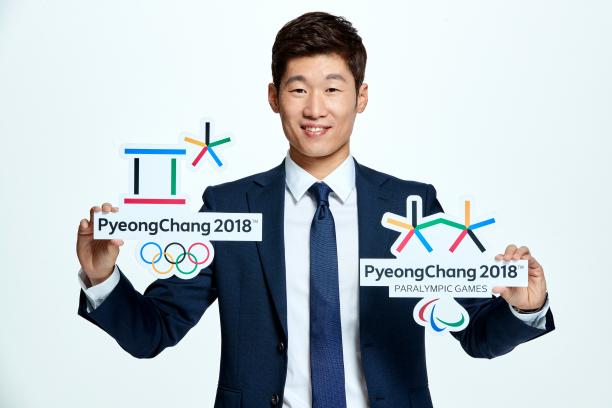 A man poses with the Olympic and Paralympic logos for PyeongChang 2018