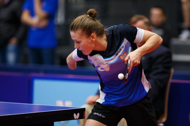 a female wearing a navy and blue shirt playing table tennis