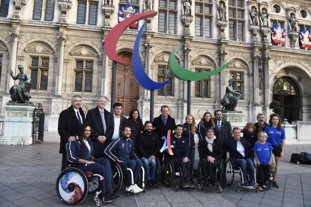 Group of people smiling in front of the Agitos logo and the municipality of Paris