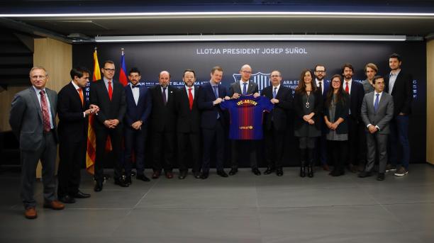 Agitos and FC Barcelona sign patnership agreement a group of men and women stand holding a Barcelona shirt