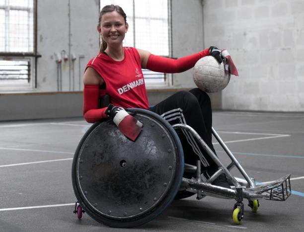 a female wheelchair rugby player poses with the ball