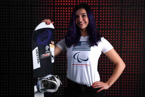Brenna Huckaby a female Para snowboarder poses with her board