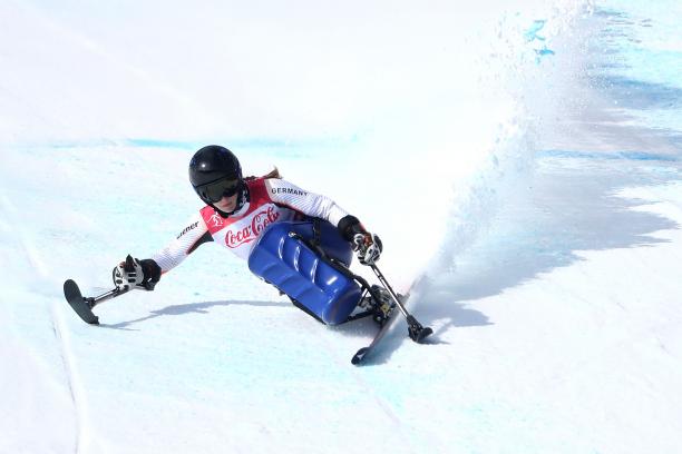 a female sit skier rounds a gate