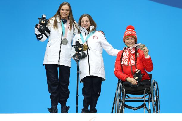three female sit skiers on the podium with their medals