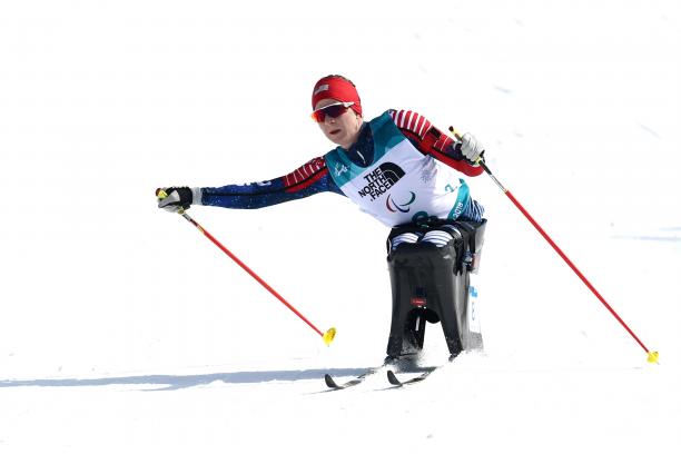 a female sit skier pushes through on the biathlon course