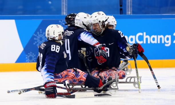 a group of Para ice hockey players celebrating a goal