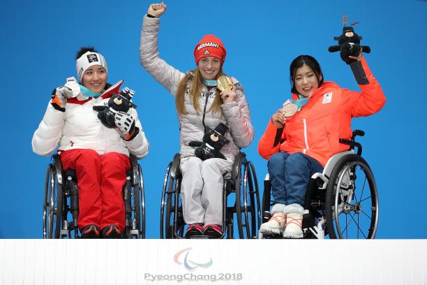 three female sit skiers on the podium with their medals
