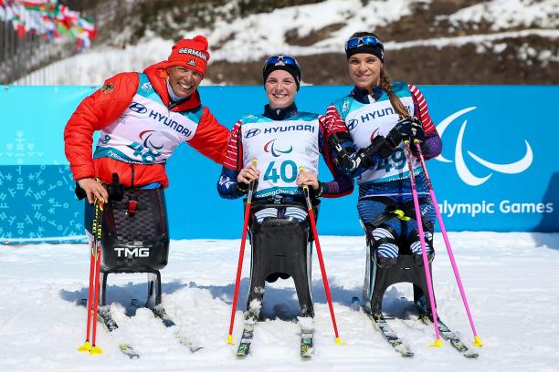 three female sit skiers celebrate their medals
