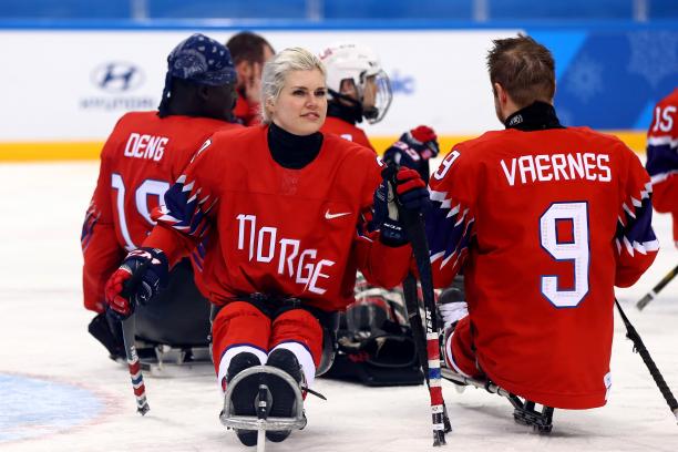 a female Para ice hockey player with her teammates on the ice
