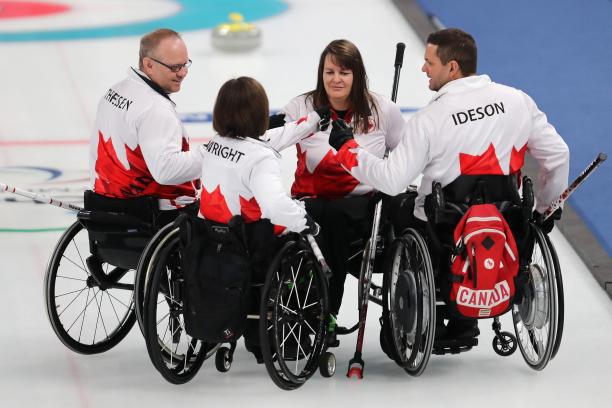 four wheelchair curlers gather in a huddle