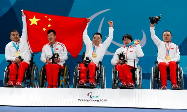 a team of wheelchair curlers hold up the Chinese flag with their medals
