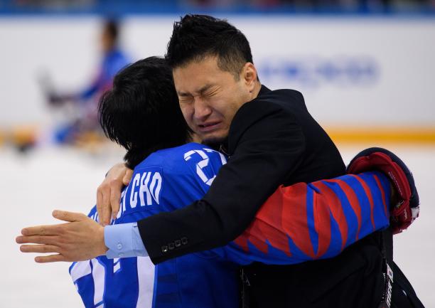 two men embrace and cry on an ice rink