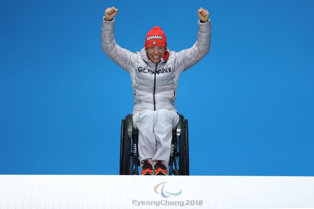 Andrea Eskau - PyeongChang 2018 a wheelchair athlete raises her arms on the podium