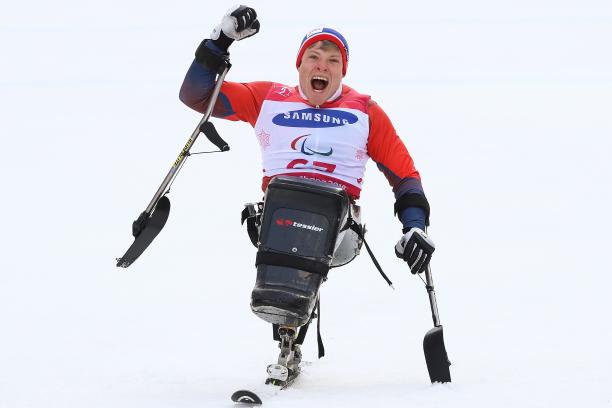 a male sit skier punches the air in celebration