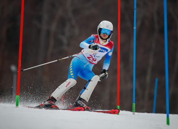 a female standing skier goes through a gate