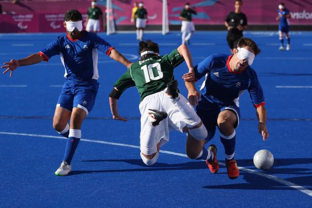 three blind football players go for the ball