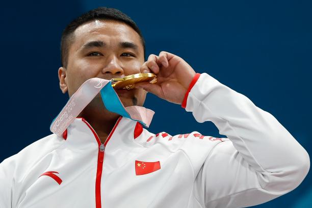 a male curler bites his gold medal